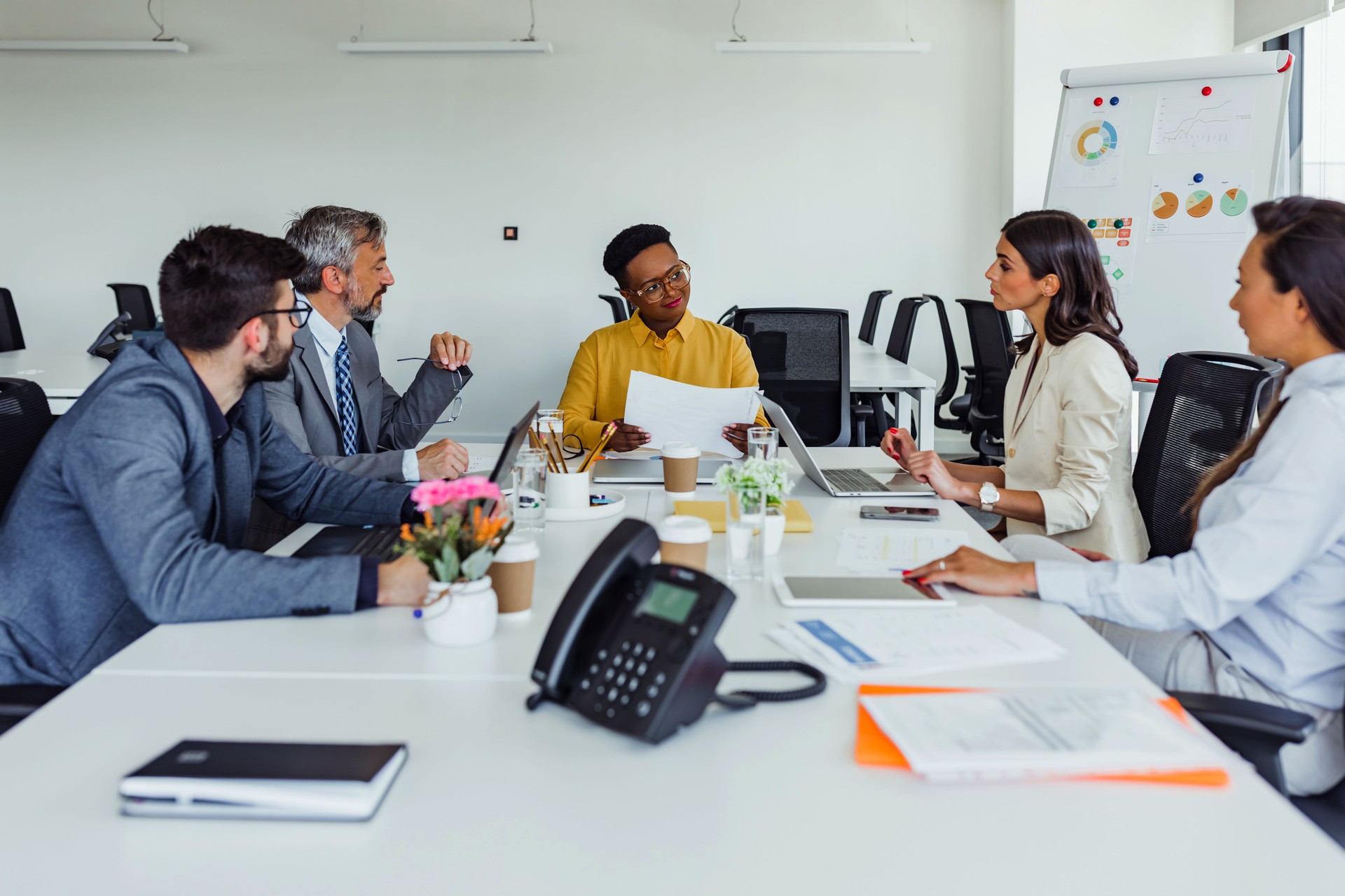 Concentrated african american woman doing paperwork, sitting in modern office on conference. Focused business lady learning financial graphs, working on corporate project at briefing meeting